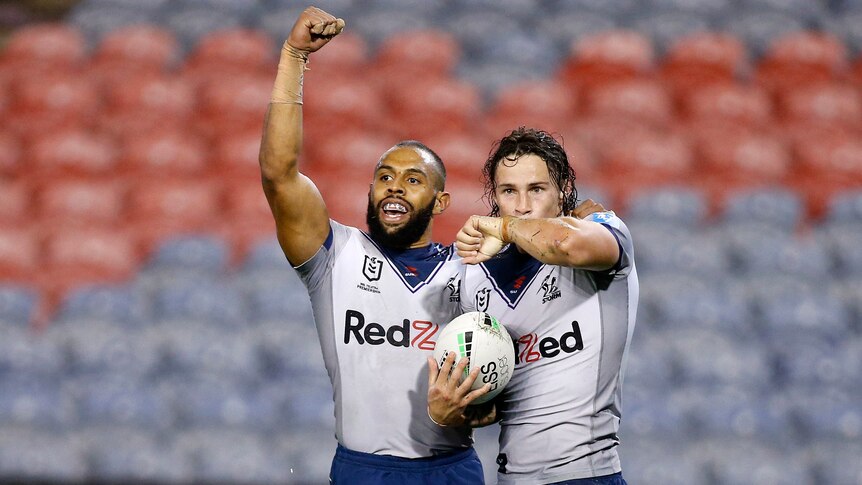 Two Melbourne Storm NRL players celebrate a try against the Sydney Roosters.