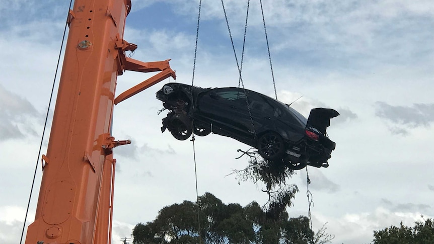 A car being lifted into the air by a crane.