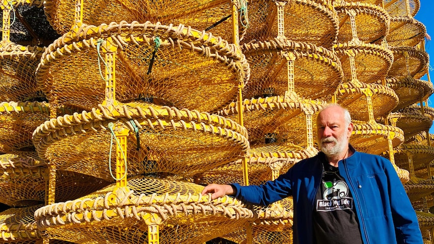 A man standing next to a stack a crab pots.