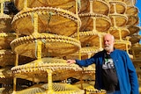A man standing next to a stack a crab pots.