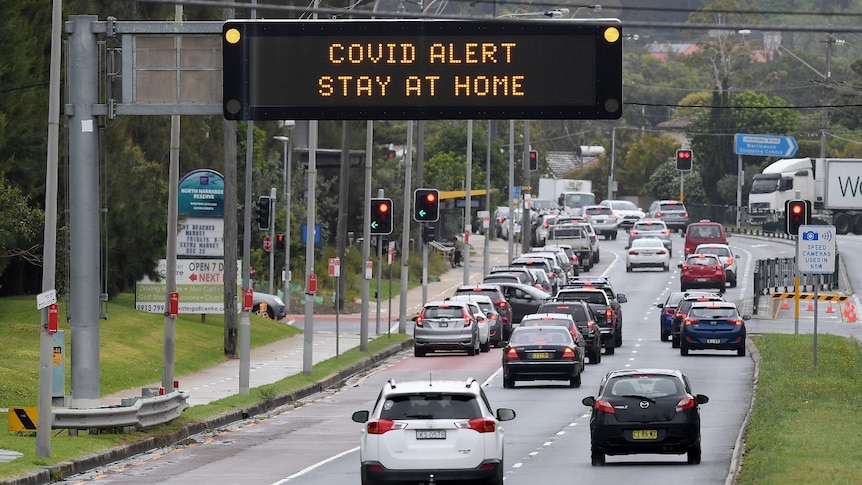 An electronic sign above a road says: "COVID alert stay at home".