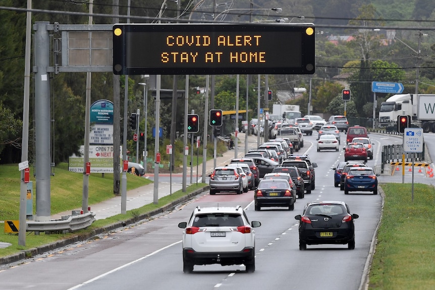 An electronic sign above a road says: "COVID alert stay at home".