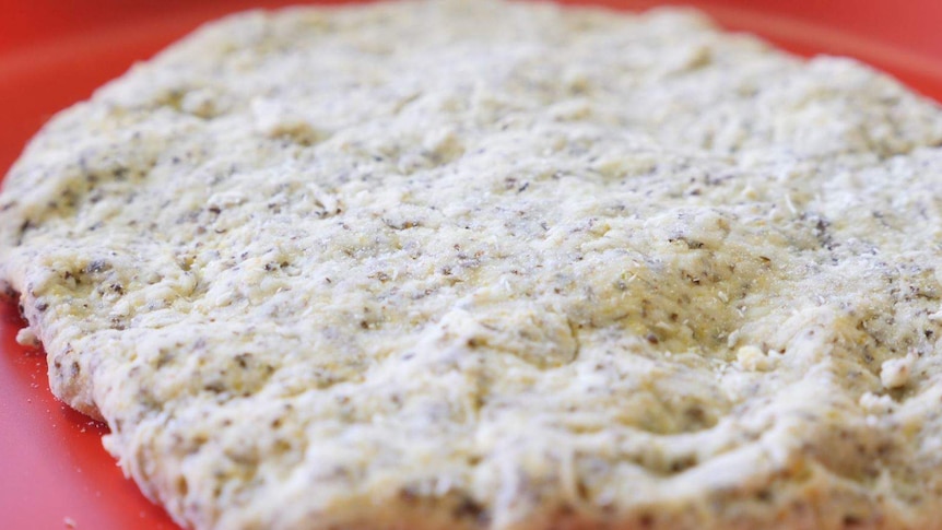 Close up on a flat bread filled with different grains.