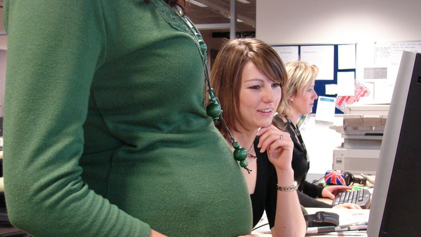 Pregnant woman holding belly at work.