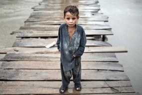 A Pakistani child walks on a wooden bridgeon the outskirts of Peshawar, August 7, 2010. (Behrouz Mehri)