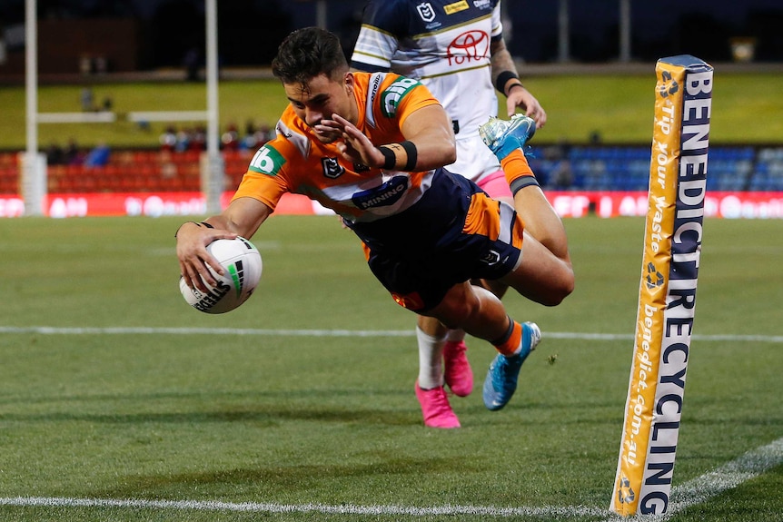 A Newcastle Knights NRL player dives for the try line to score against the North Queensland Cowboys.