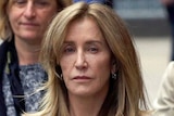 Felicity Huffman leaves court in Boston holding the hand of her brother Moore Huffman Jr