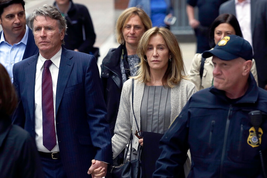 Felicity Huffman leaves court in Boston holding the hand of her brother Moore Huffman Jr