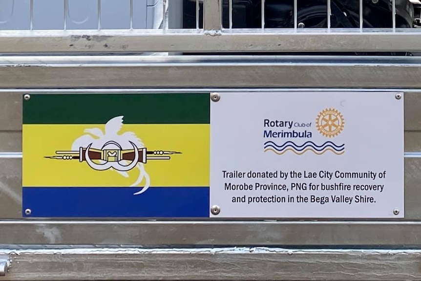 Close up of a plaque showing a green, yellow, and blue flag of the Morobe province in PNG fixed to the back of a ute