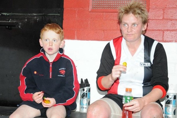 A junior Australian rules player sits in the dressing rooms next to his aunt.