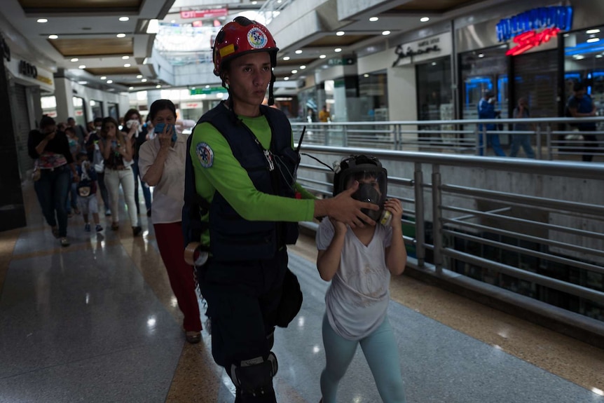 A man helps a girl wearing a gas mask