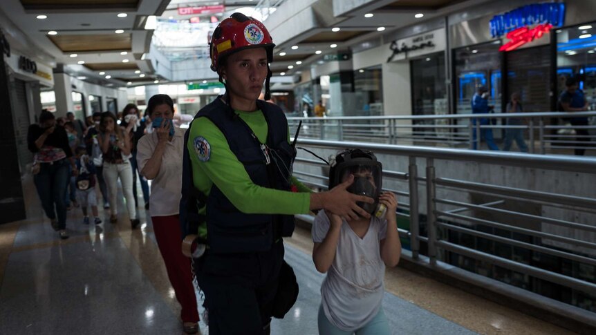 A man helps a girl wearing a gas mask