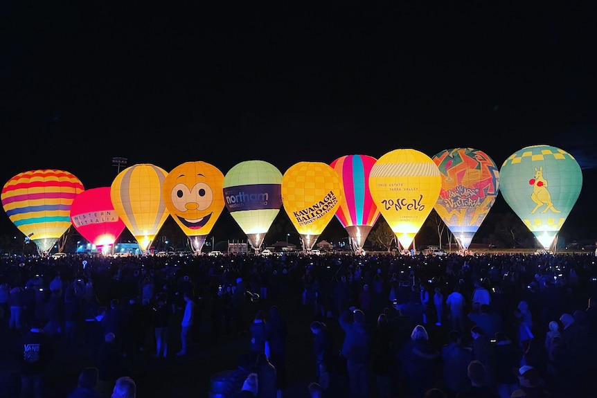 A line of hot air balloons lit up at night.