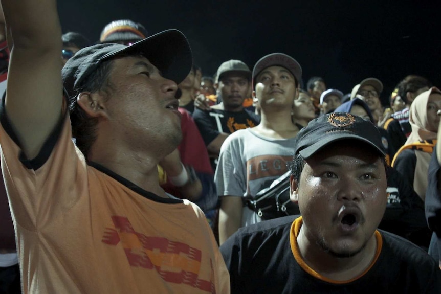Two fans cheer and jeer at a Bali vs Jakarta game.