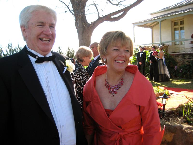 Un niño con traje negro y pajarita y una mujer con un vestido naranja están sonriendo. 