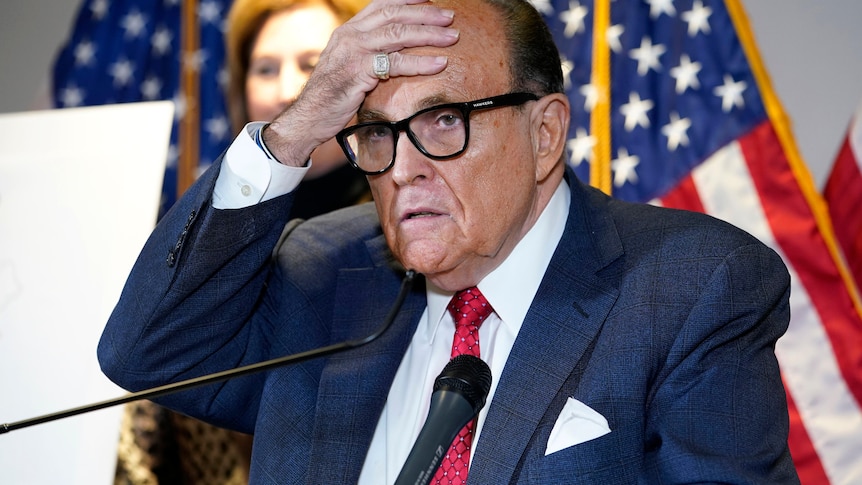Rudy Giuliani places his hand on his forehead