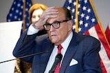 Rudy Giuliani places his hand on his forehead