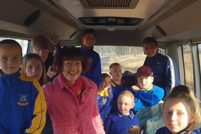 A woman in pink on a school bus with children.