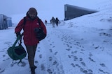 Steven Schubert walking through sleet with camera in Svalbard Norway while covering Doomsday Vault story.
