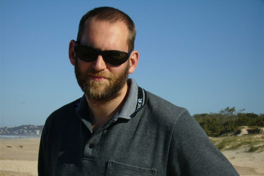 A man in a grey poloneck shirt and sunglasses.