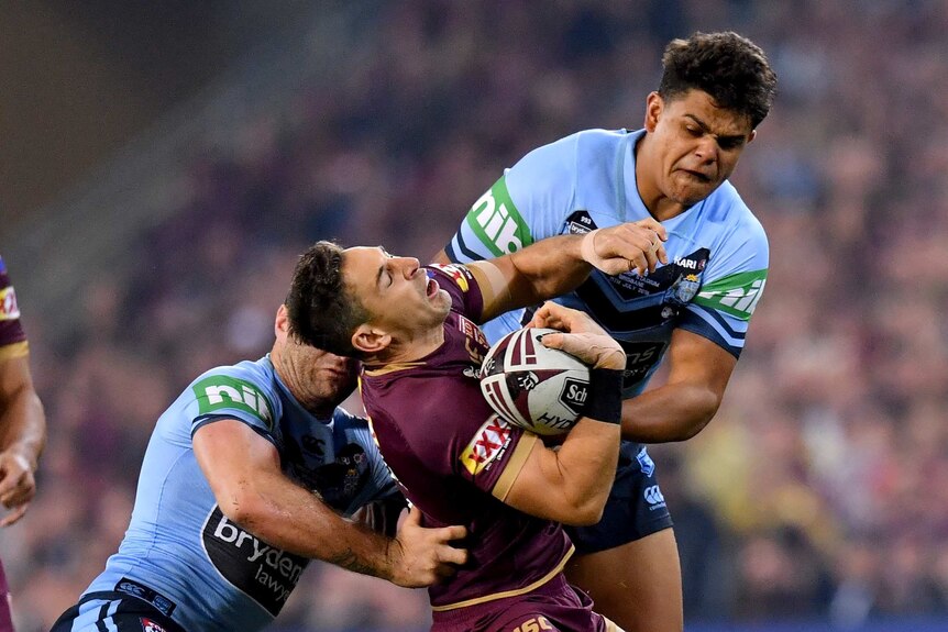 Billy Slater (C) of the Maroons is tackled by the Blues in State of Origin III in Brisbane on July 11, 2018.