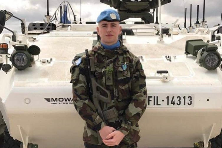 Private Seán Rooney in blue beret in front of UN vehicle