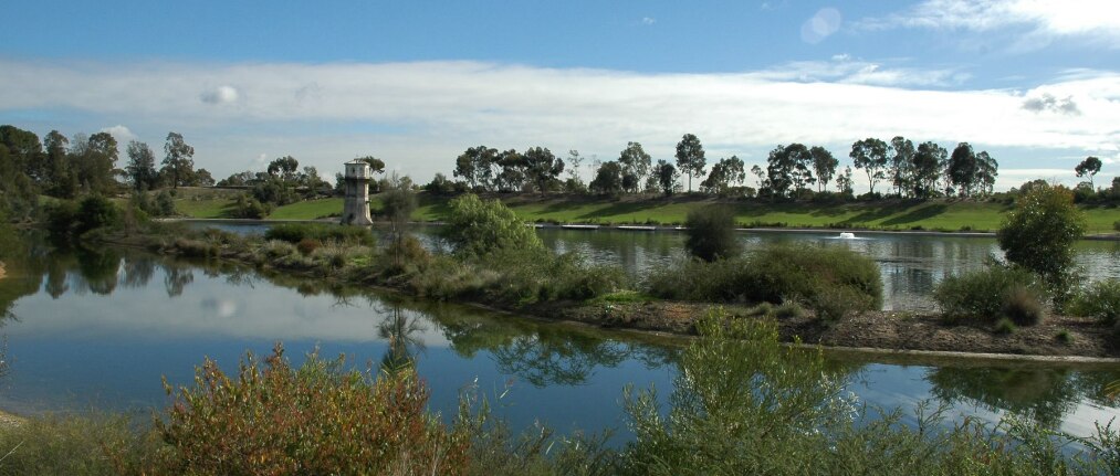 a green reserve with a large body of water and blue sky with big white clouds
