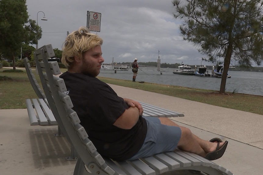 Clay sitting on a bench by the water.