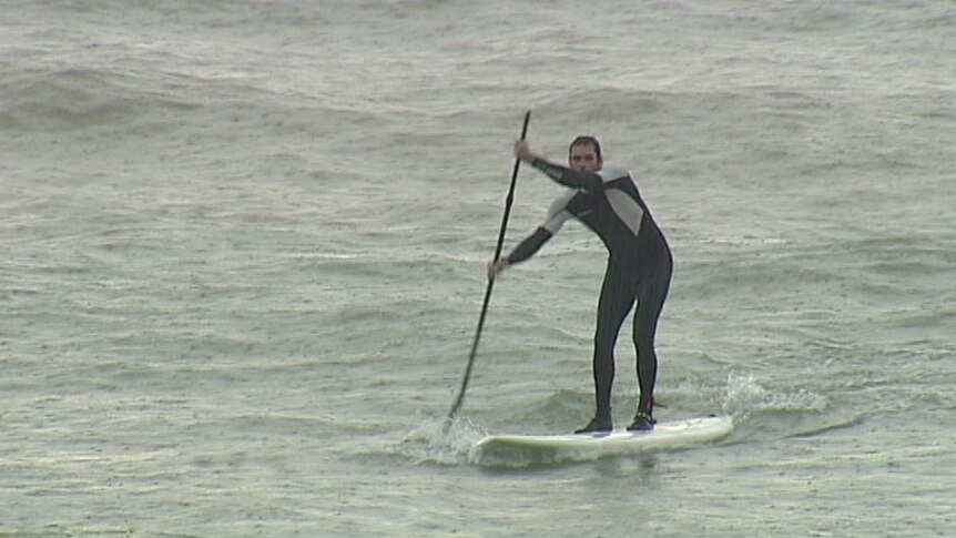 Paddle boarder hits the surf at Nightcliff Beach