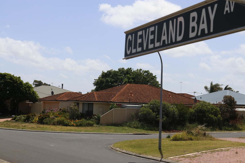 A street sign saying Cleveland Bay Av, with houses in the background.