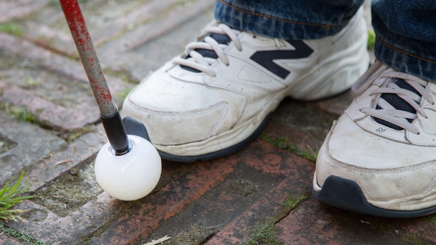 White canes are held out at arm's length with the white ball in front of the right foot at intersections.