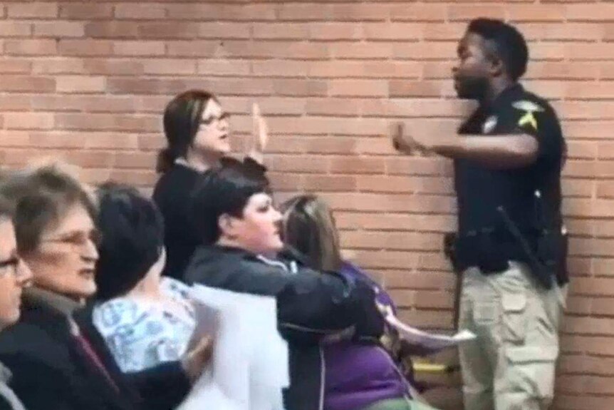 Marshal stands in front of teacher Deyshia Hargrave at Louisiana school meeting, they gesture at each other
