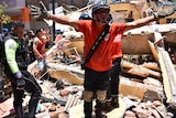 A rescuer worker shouts from the debris of a home that collapsed when an earthquake shook Machala, Ecuador.
