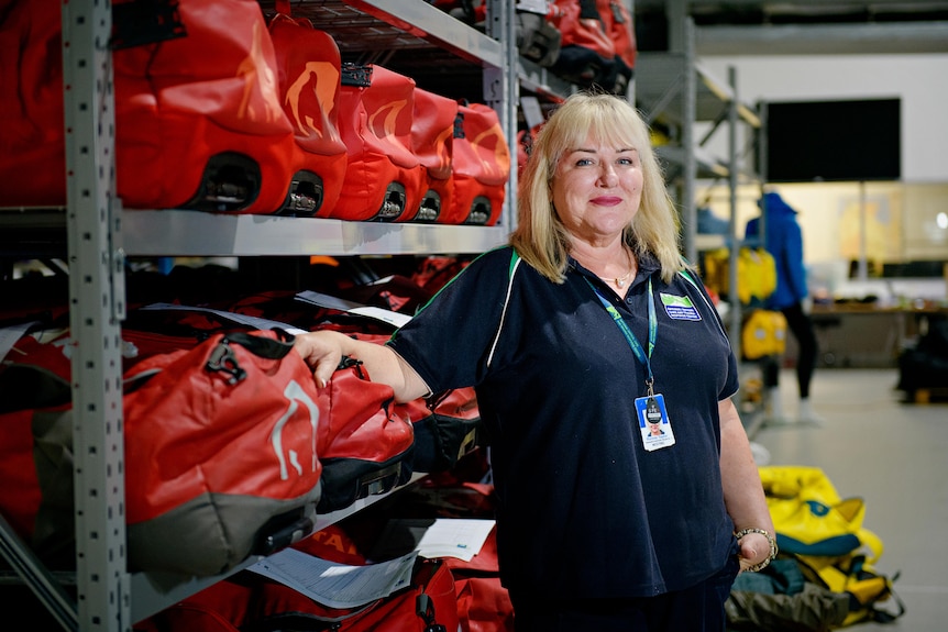 a blonde woman standing near red bags