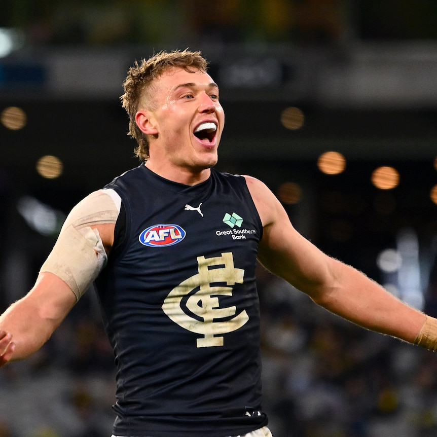 A smiling Carlton captain Patrick Cripps holds his arms out in celebration after a goal.