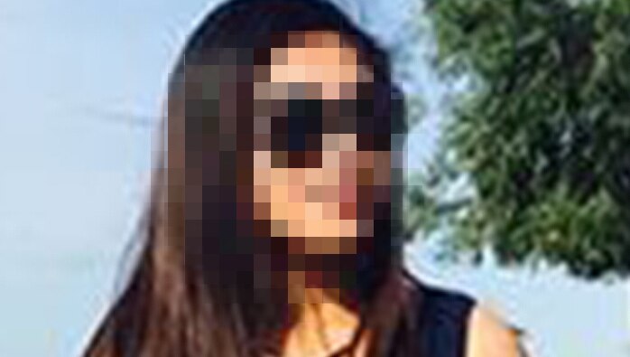 A young woman with a pixelated face stands in a park