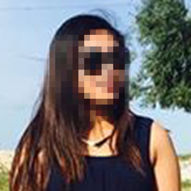 A young woman with a pixelated face stands in a park