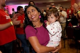 Zaneta Mascarenhas holds her child as supporters celebrate around her