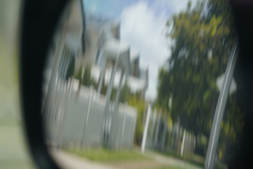 A few houses in rearview mirror of a car. 