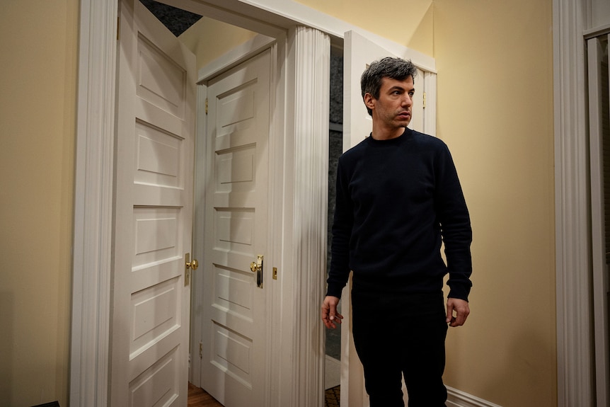 Comedian Nathan Fielder stands next to a series of doors in a scene from his HBO show