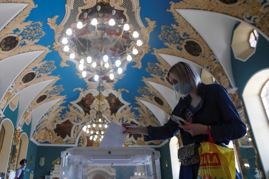 A woman wearing a protective face mask casts her ballot at a mobile polling station inside Kazansky railway terminal.