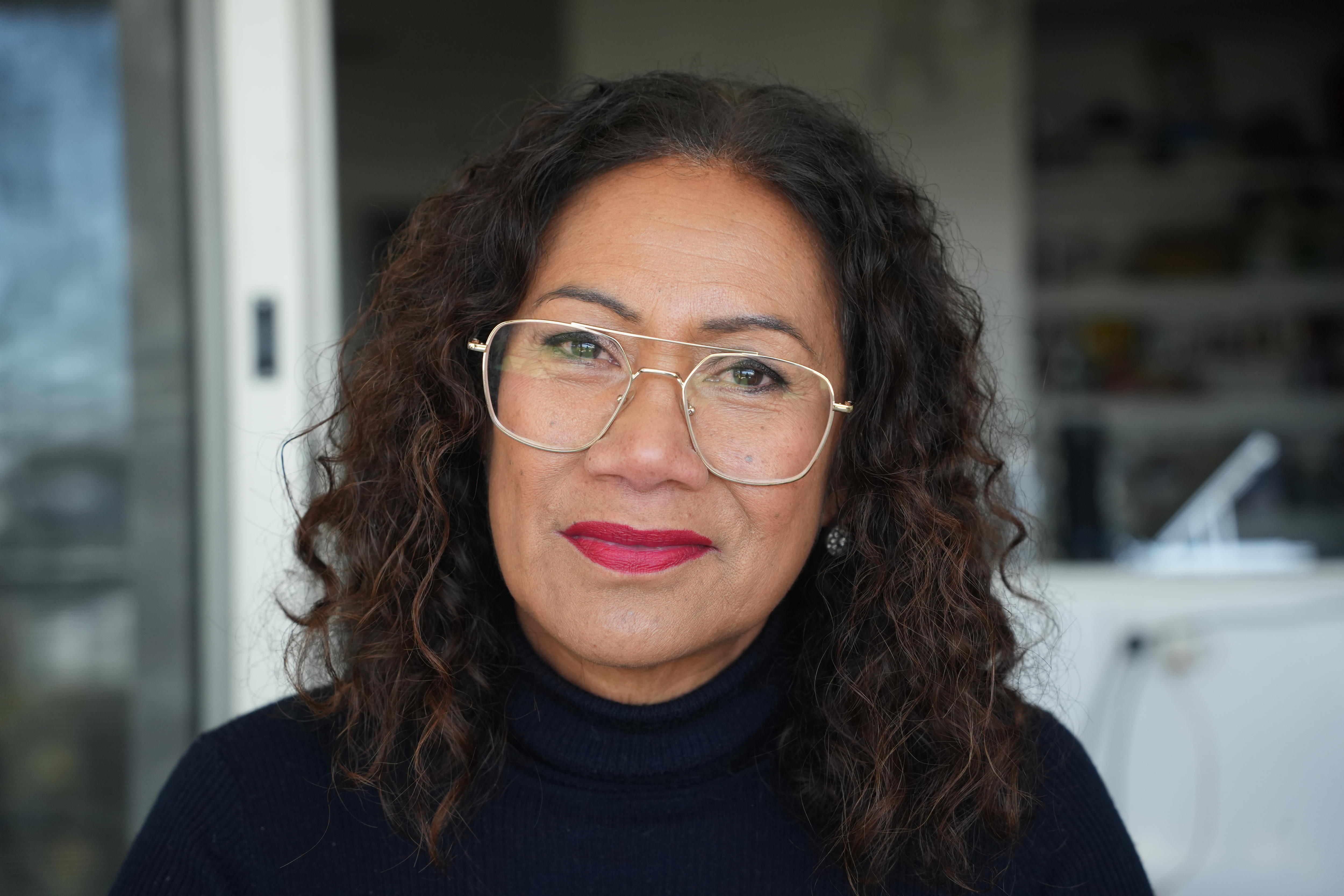 A woman wearing glasses looking straight ahead.