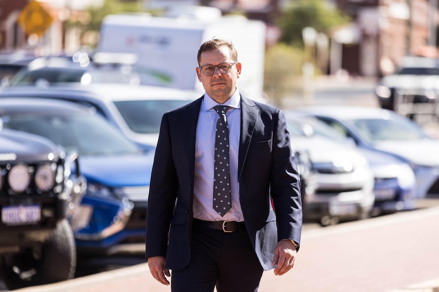 A man in a suit walking into a court trial.  