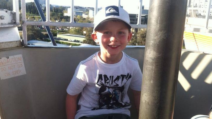 A young blonde boy smiles at the camera.