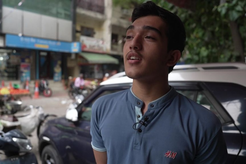 Youngman wearing blue t-shirt speaking during a street interview.