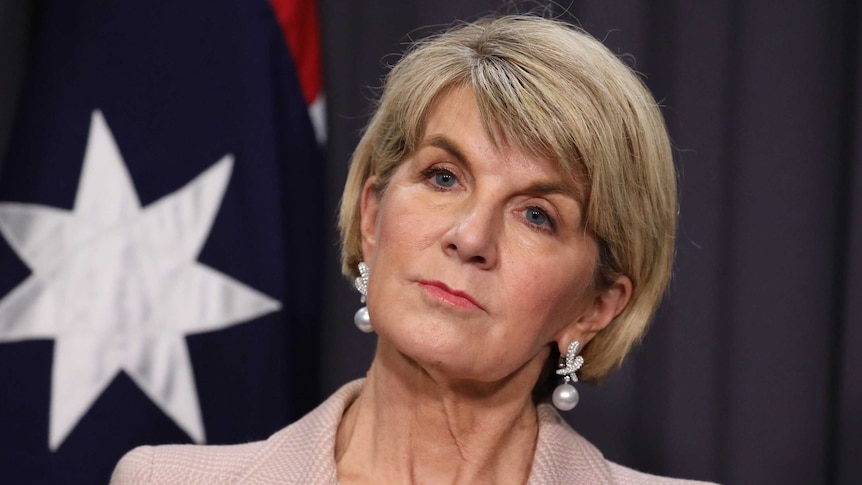 Tight shot of Bishop looking stern. She's standing in front of an Australian flag.