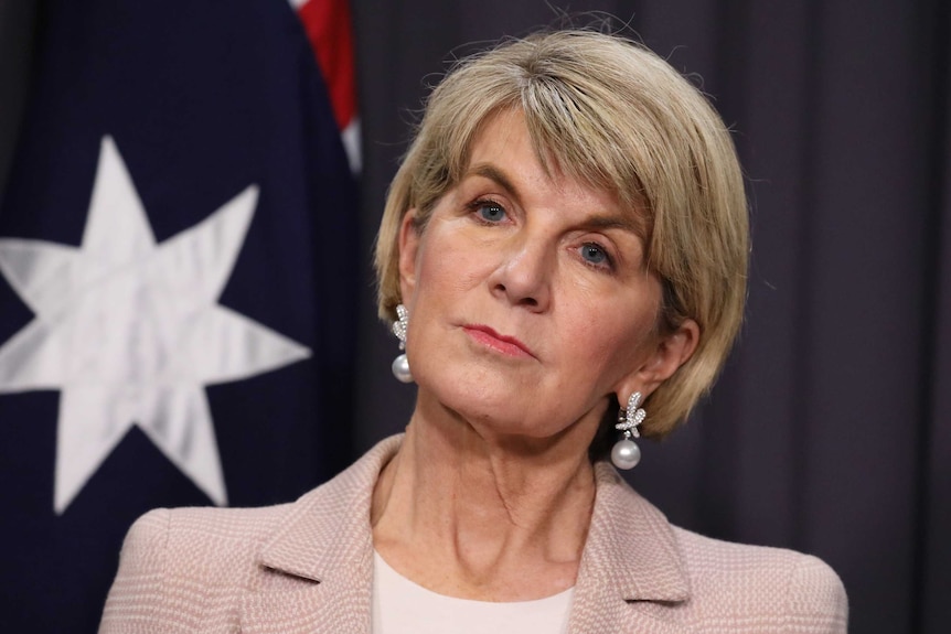 Tight shot of Bishop looking stern. She's standing in front of an Australian flag.