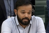 A screenshot of Azeem Rafiq speaking while sitting at a hearing
