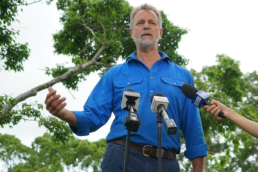 Nigel Scullion stands in front of microphones as he addresses the press