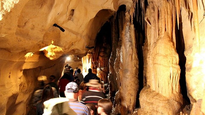 A group of people walking through a cave, there are stalagmites on the right